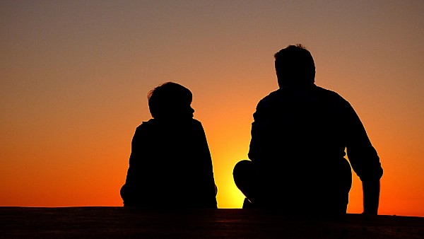 Adulte et jeune assis au coucher du soleil